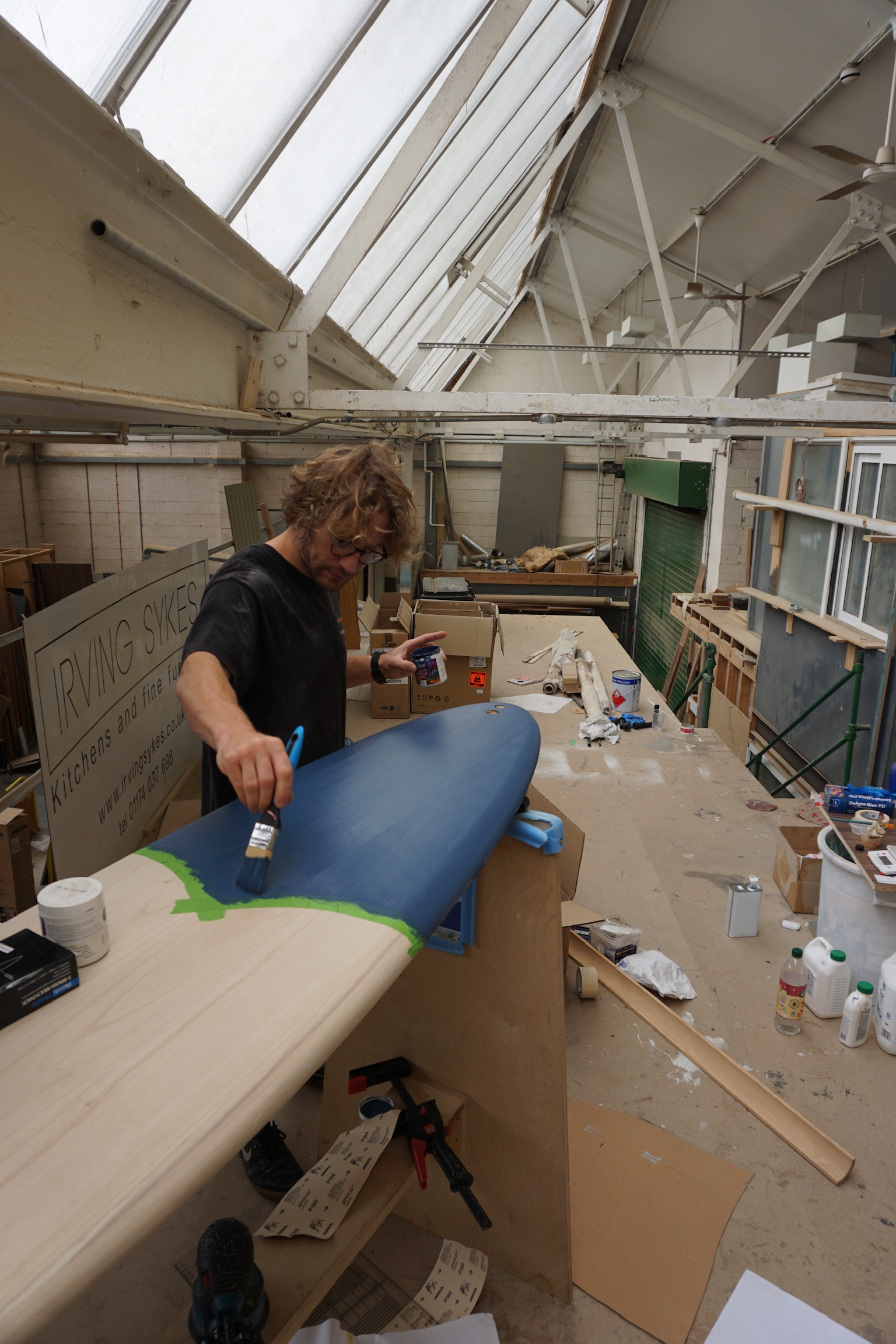 Colour being applied by hand to a timber surfboard